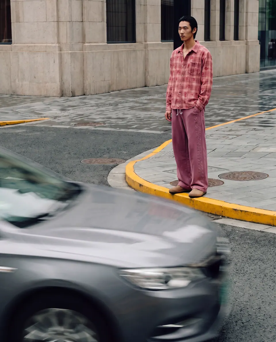 Standing on a street corner as a car blurs past in the foreground.
