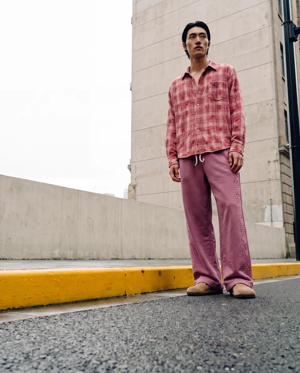 Low-angle full-length shot on a kerb in front of a concrete building.