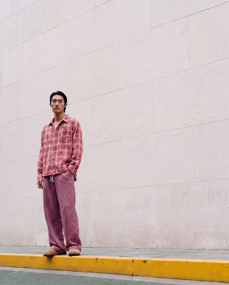 Small in frame against a tall white wall above a yellow kerb.