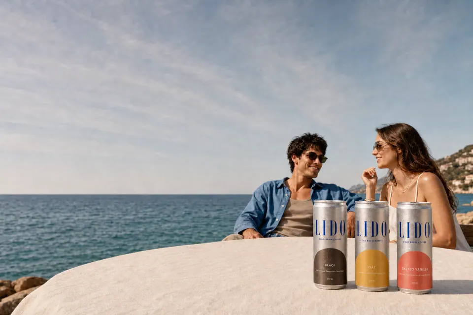 A couple at a seaside table with the three LIDO cans lined up in front of them.