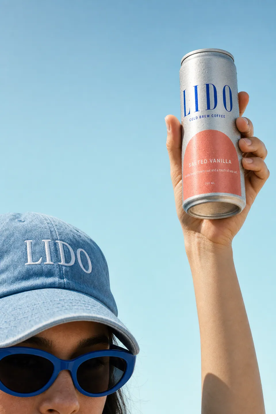 A raised hand holding a LIDO Salted Vanilla can up to the sky beside the blue cap.