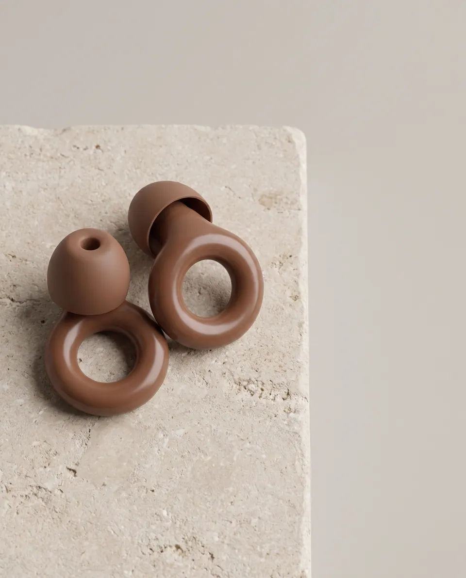 Brown earplugs on a travertine slab with space for copy.