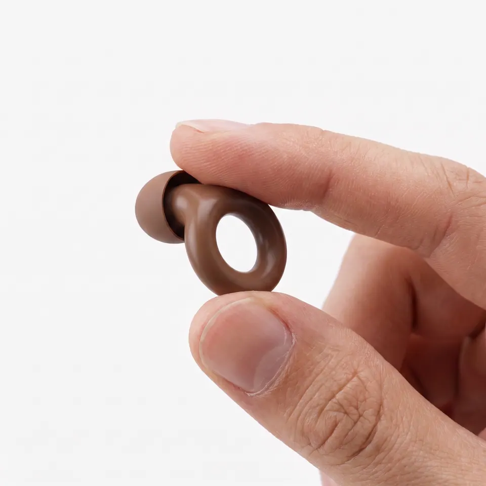 A brown earplug held between thumb and forefinger to show its size.