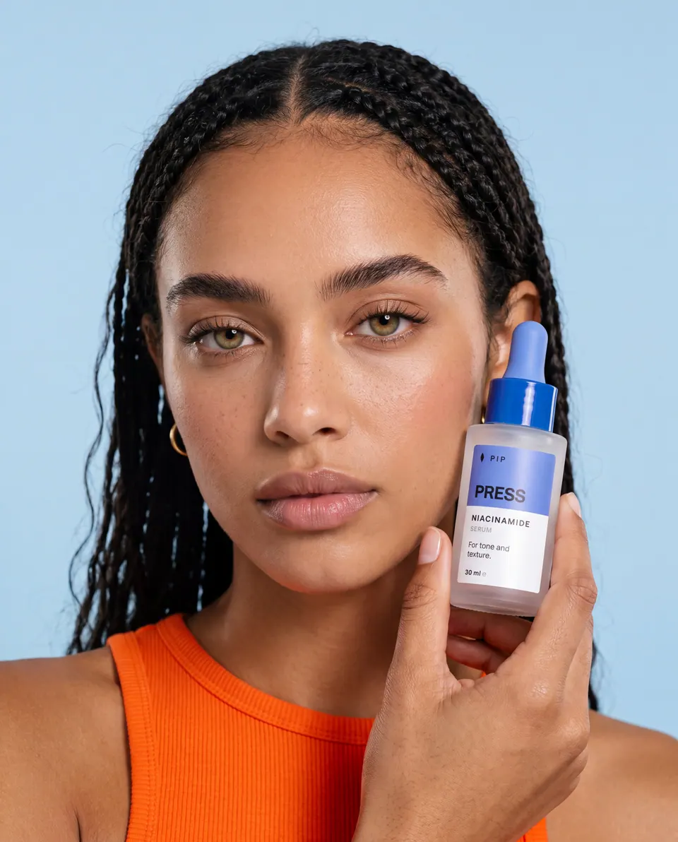 The same model looking into the camera, holding PRESS close to her face.