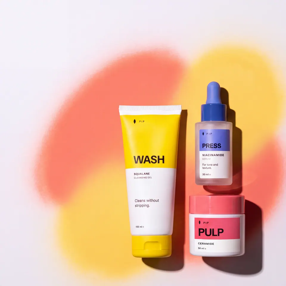 The same three Pip products on a pale background with soft coral and yellow airbrushed shapes.